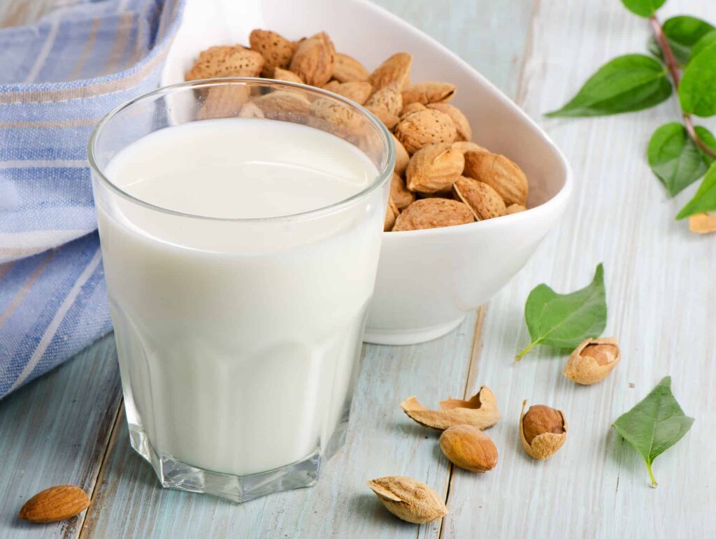 milk almond -glass of milk with bowl of almonds